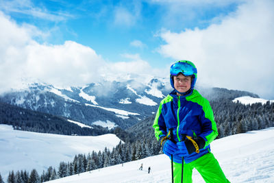 Portrait of boy standing on snow covered mountain