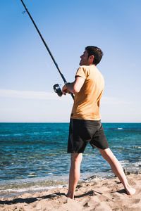 Full length of man standing at beach against sky