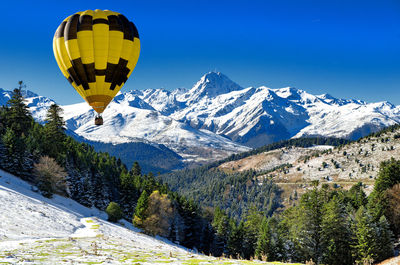 Hot air balloon flying over snowcapped mountains against sky