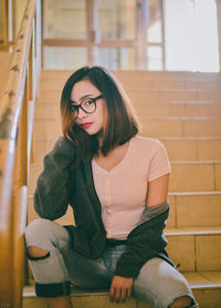 Portrait of young woman sitting against brick wall