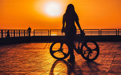 Low angle view of silhouette woman walking on beach against sky during sunset