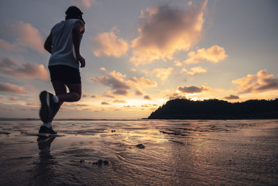 Full length of man on beach against sky during sunset