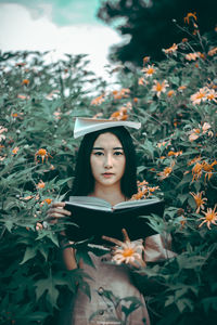Portrait of beautiful young woman against plants