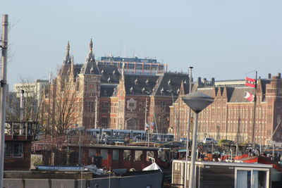 Sailboats in city by buildings against clear sky