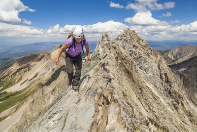 Man standing on rock against sky
