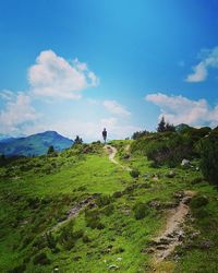 Rear view of man standing on mountain against sky