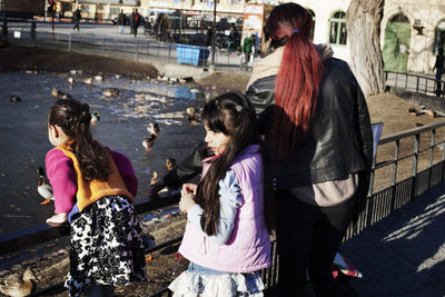 Girls with mother feeding ducks in park