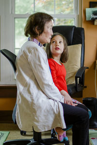 A small girl tenderly holds grandmother's hand as they sit together