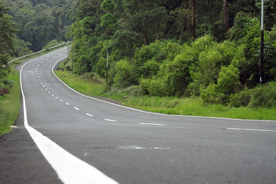 Empty road amidst trees in forest