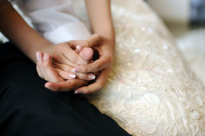 High angle midsection of newlywed couple holding hands at wedding ceremony