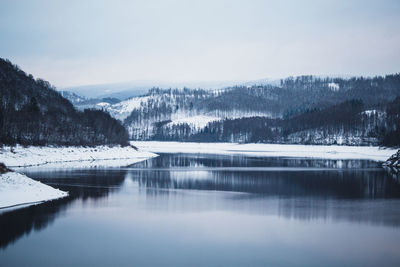 Scenic view of lake by snowcapped mountains against sky