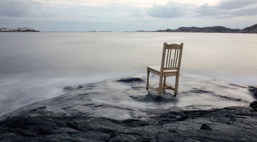 Empty chair on lakeshore in front of sea