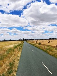 Road by agricultural field against sky