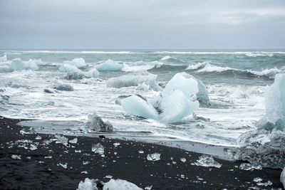 Ice blocks on diamond  beach, sea waves, black sand. jokulsarlon. atlantic ocean coast, iceland