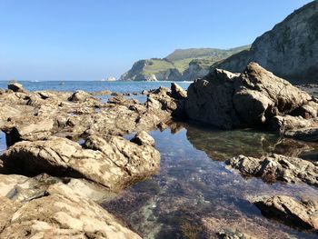 Rocks on beach against clear sky