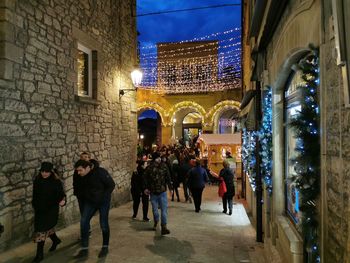 People walking on illuminated street in city at night