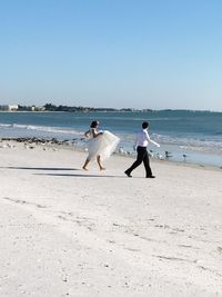 People on beach against clear sky