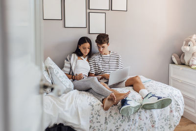 Siblings studying on tablet pc in bedroom at home