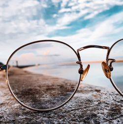 Close-up of sunglasses on land against sky