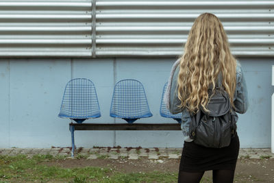 Rear view of woman standing against blue wall