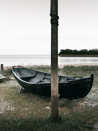 Abandoned boat moored on shore against sky