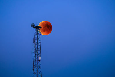 Low angle view of communications tower against clear blue sky