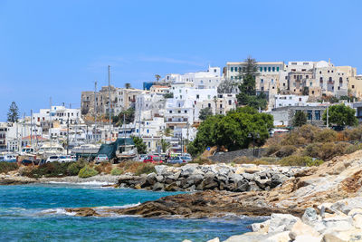 Buildings by sea against clear blue sky