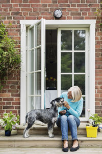 Happy senior woman with dog at house entrance