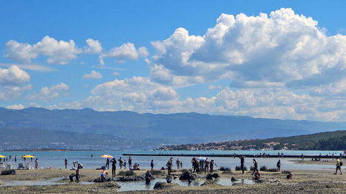 Group of people on beach against sky