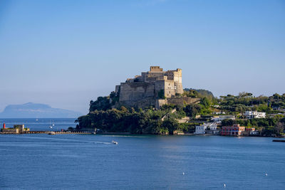 Buildings by sea against clear sky