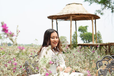Portrait of young woman standing by plants