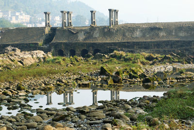 View of ancient structure with rocks and water