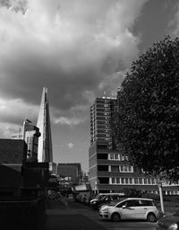 Cars on road in city against cloudy sky