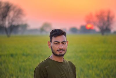 Portrait of young man on field during sunset
