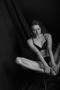 Portrait of a young woman sitting against black background