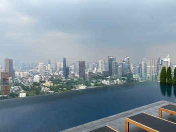 Modern buildings by swimming pool against sky