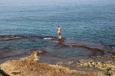 Man standing on rock at sea shore