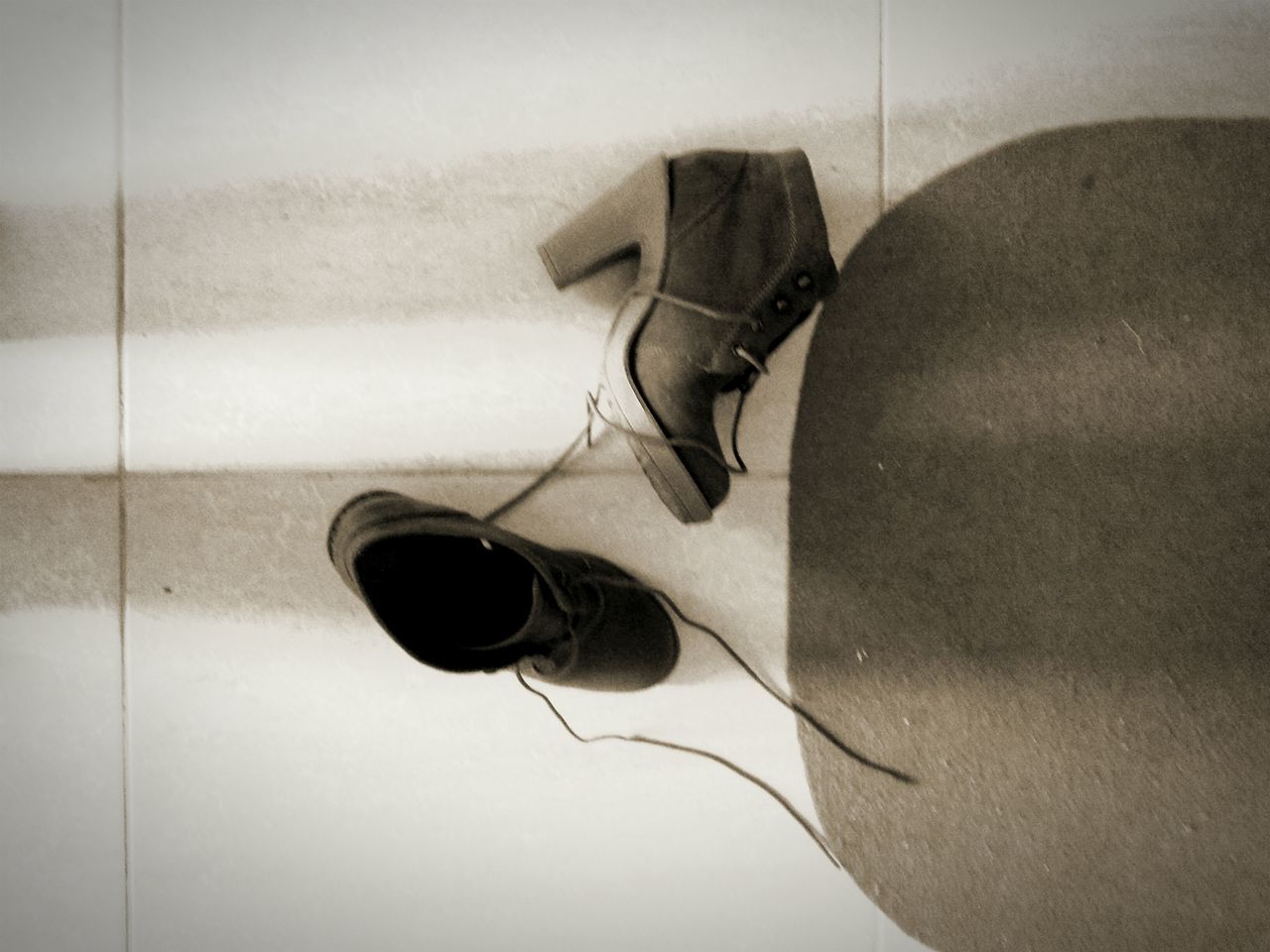 indoors, still life, wall - building feature, shoe, close-up, high angle view, man made object, single object, pair, shadow, hanging, equipment, no people, technology, simplicity, cable, electricity, footwear, wall, flooring