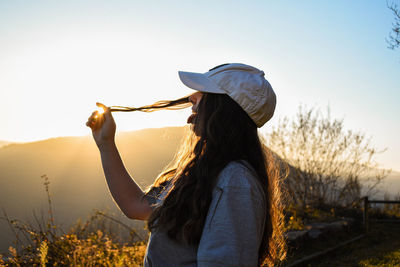 Side view of woman standing by plants against sky