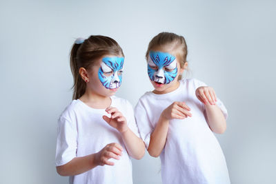 Two sister girls with aqua makeup in the form of a blue water zodiac tiger depict a tiger.