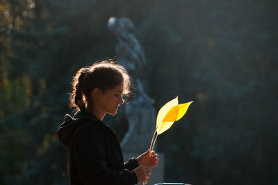 Portrait of woman holding yellow leaf