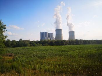 Smoke emitting from chimney on field against sky