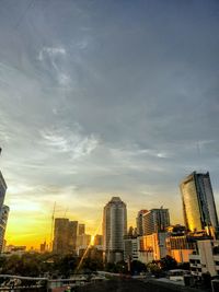 Modern buildings in city against sky during sunset