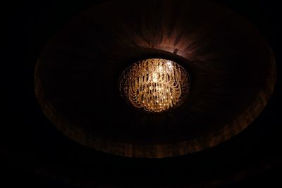 Low angle view of illuminated electric light against black background