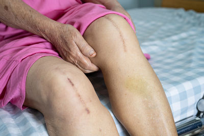Low section of woman relaxing on bed at home