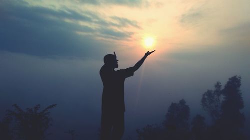 Silhouette man standing against sky during sunrise