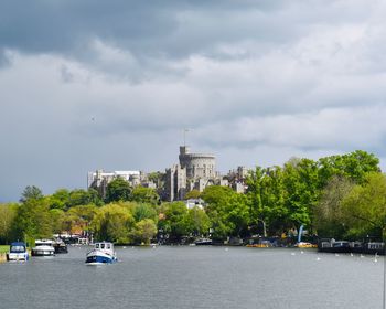 View of trees in city against cloudy sky