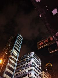 Low angle view of illuminated buildings against sky at night