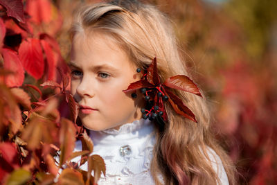 Close-up of thoughtful cute girl by plants in park during autumn