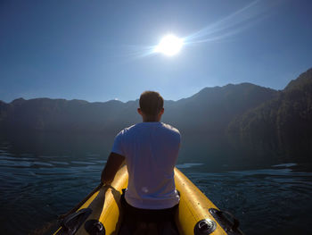 Rear view of man kayaking on river against sky